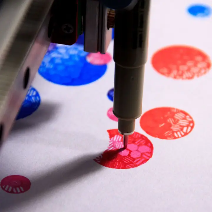 Detail view of the pen plotter drawing a red section on top of a pink circle that looks like a half moon with a gap for another circle to overlap it on a layer not drawn yet.